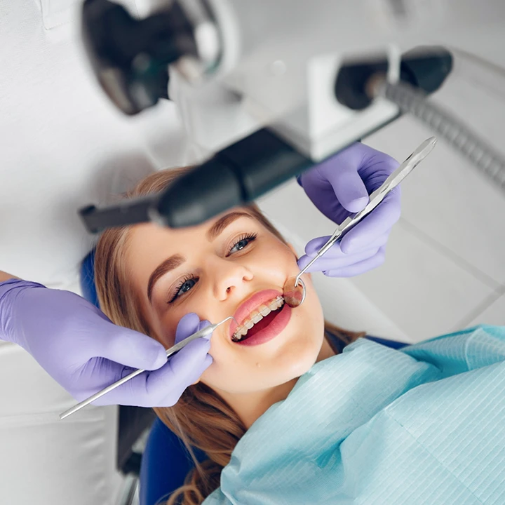 Dra. Alice  examinando os dentes de uma paciente durante atendimento odontológico